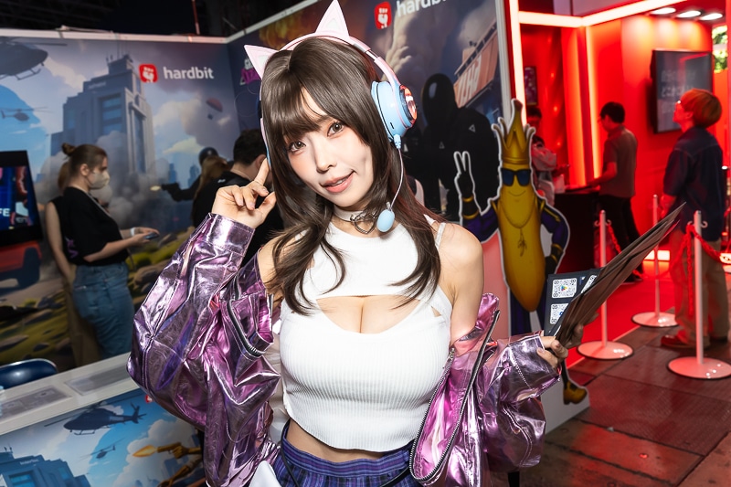 「東京ゲームショウ2025」の美人コスプレイヤー＆コンパニオン特集｜胸開きニット衣装がセクシーなコンパニオンが『Grand Outlaws』を大展開する「GRAND OUTLAWS」ブースでお出迎え