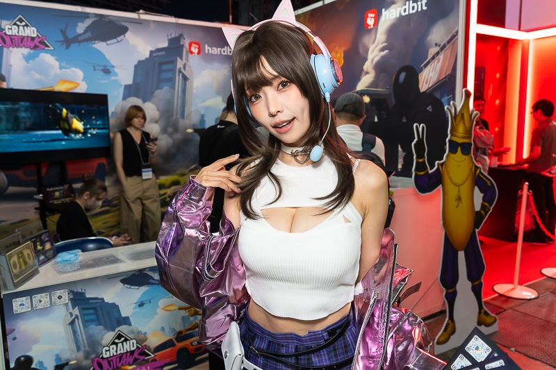 「東京ゲームショウ2025」の美人コスプレイヤー＆コンパニオン特集｜胸開きニット衣装がセクシーなコンパニオンが『Grand Outlaws』を大展開する「GRAND OUTLAWS」ブースでお出迎え
