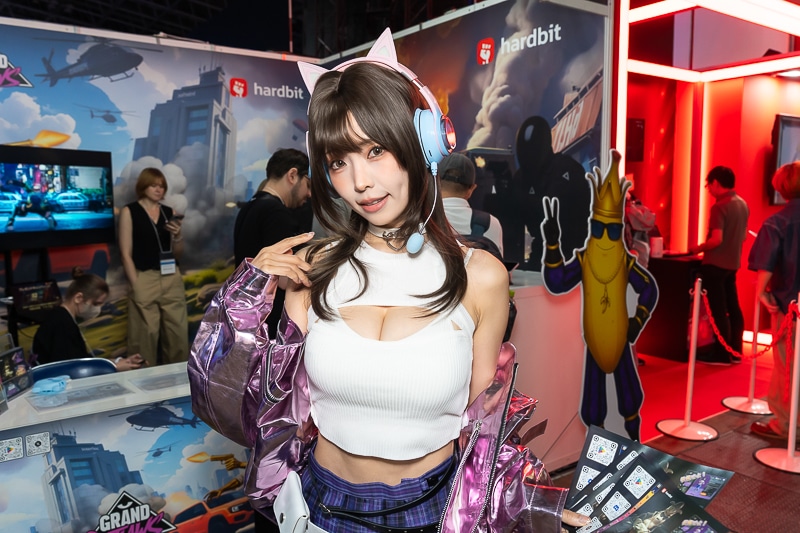 「東京ゲームショウ2025」の美人コスプレイヤー＆コンパニオン特集｜胸開きニット衣装がセクシーなコンパニオンが『Grand Outlaws』を大展開する「GRAND OUTLAWS」ブースでお出迎え