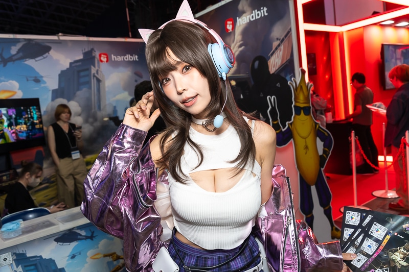 「東京ゲームショウ2025」の美人コスプレイヤー＆コンパニオン特集｜胸開きニット衣装がセクシーなコンパニオンが『Grand Outlaws』を大展開する「GRAND OUTLAWS」ブースでお出迎え
