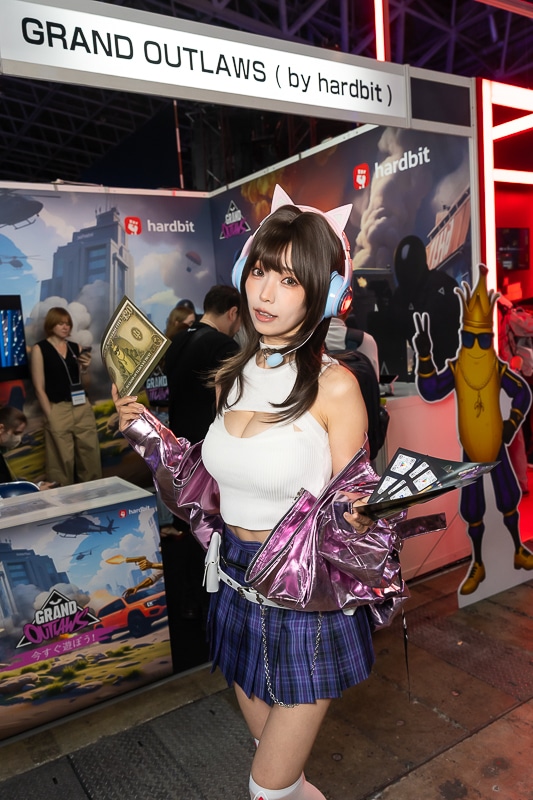 「東京ゲームショウ2025」の美人コスプレイヤー＆コンパニオン特集｜胸開きニット衣装がセクシーなコンパニオンが『Grand Outlaws』を大展開する「GRAND OUTLAWS」ブースでお出迎えの画像-1