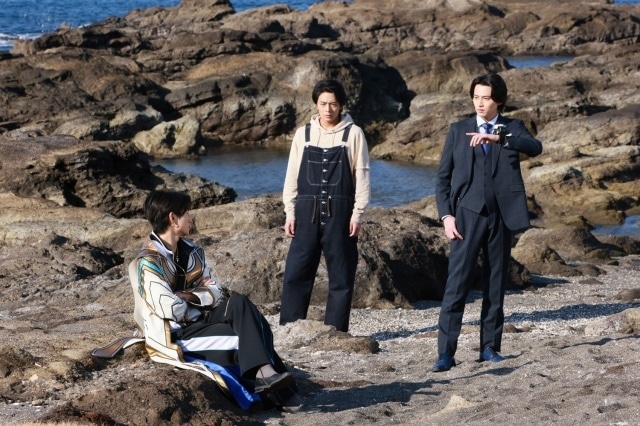 ▲海辺にいる熊手真白(左)と立ち尽くす阿久瀬錠(中央)とブンブンチェンジャーで連絡を取る鳴田射士郎(右)